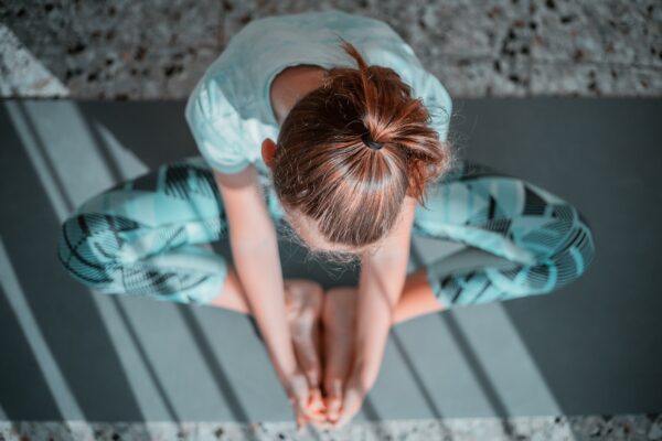 Kvinde sidder foroverbøjet i yogastilling