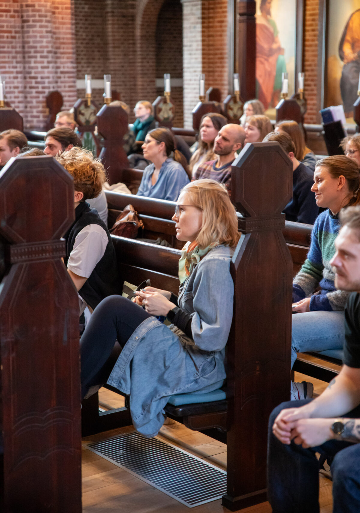 Unge mennesker lytter på kirkebænkene i Apostelkirken
