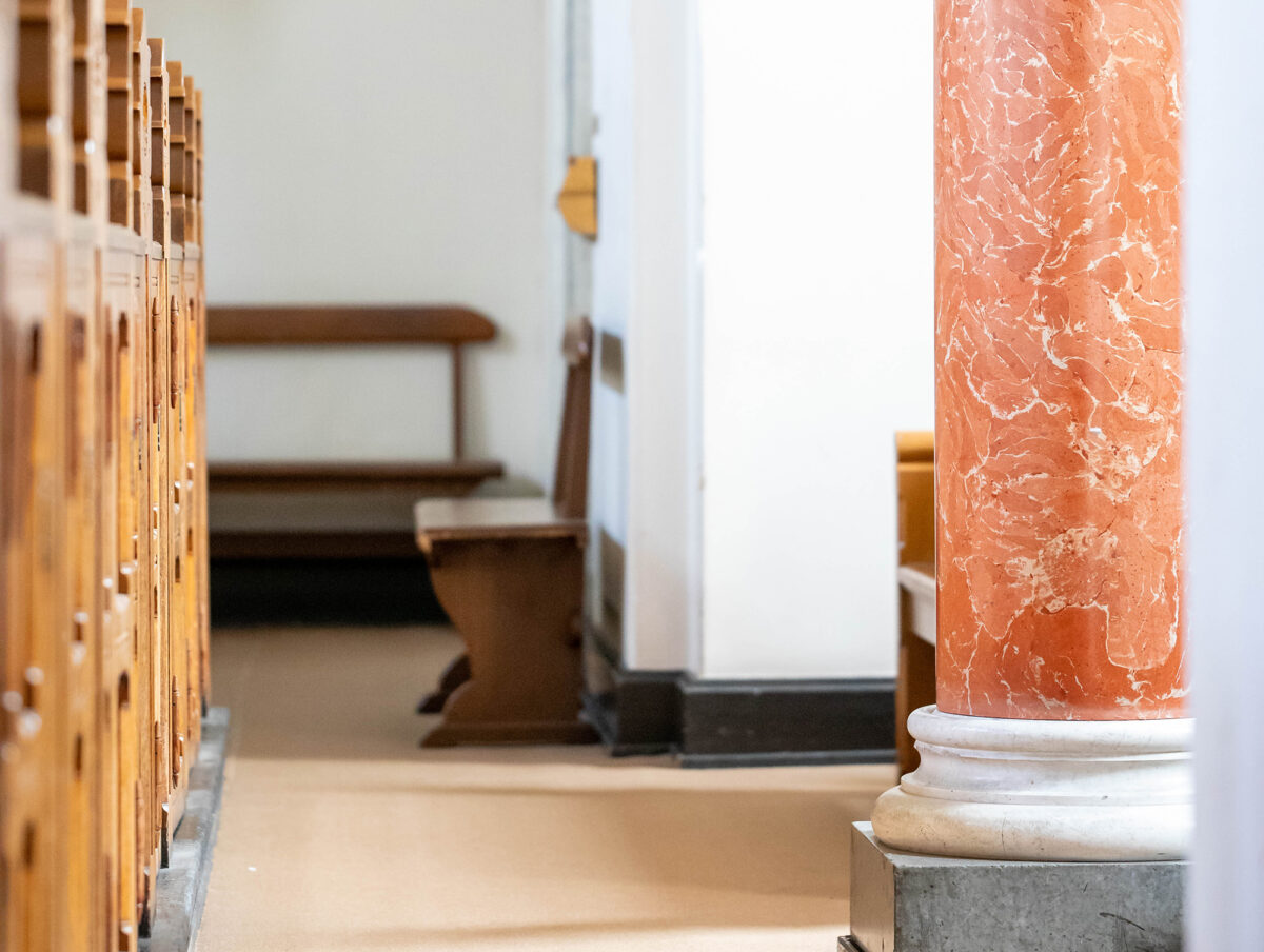 Bænkerækker, søjle, lille bænk og lys, der falder ind ad vinduet i Sct. Matthæus Kirke