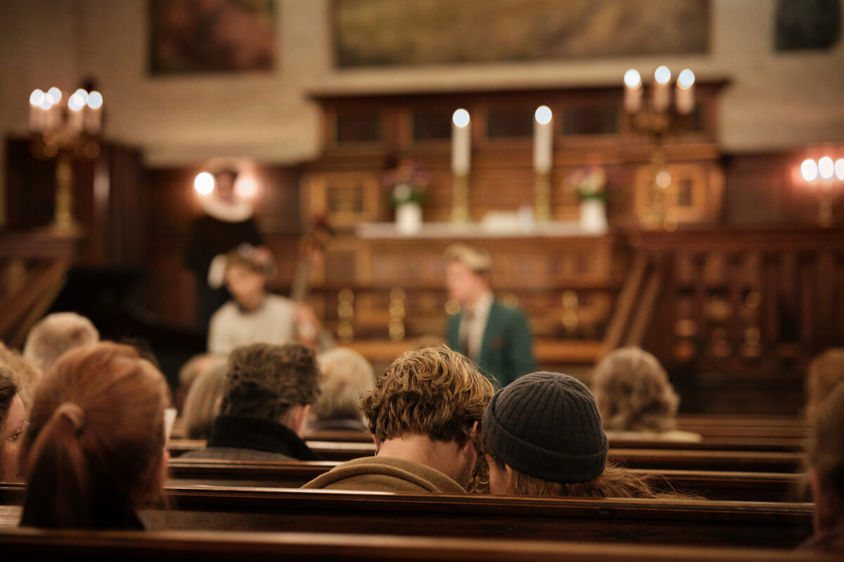 Mennesker set bagfra sider på kirkebænke.
